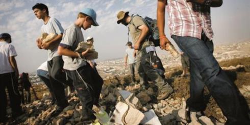 Jewish settlers collect stones to build a structure as they attempt to establish an unauthorised outpost at the hill of Eitam